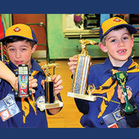 Cub Scout best friends with Pinewood Derby cars and Trophies
