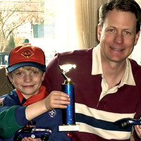 Cub scout first place finisher with trophy, car and dad